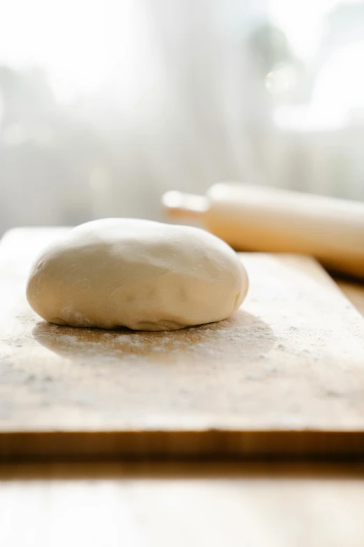 a ball of dough sitting on top of a wooden cutting board, by Tom Bonson, unsplash, made of glazed, sunny light, straight neck, vanilla