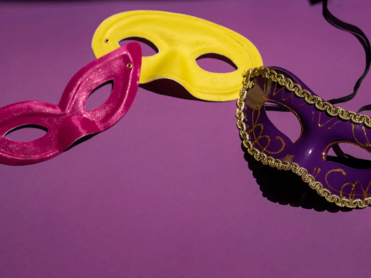 a couple of masks sitting on top of a table, a photo, trending on pexels, pop art, purple and gold color scheme, lingeries beauty, bright vivid color hues:1, eye patch