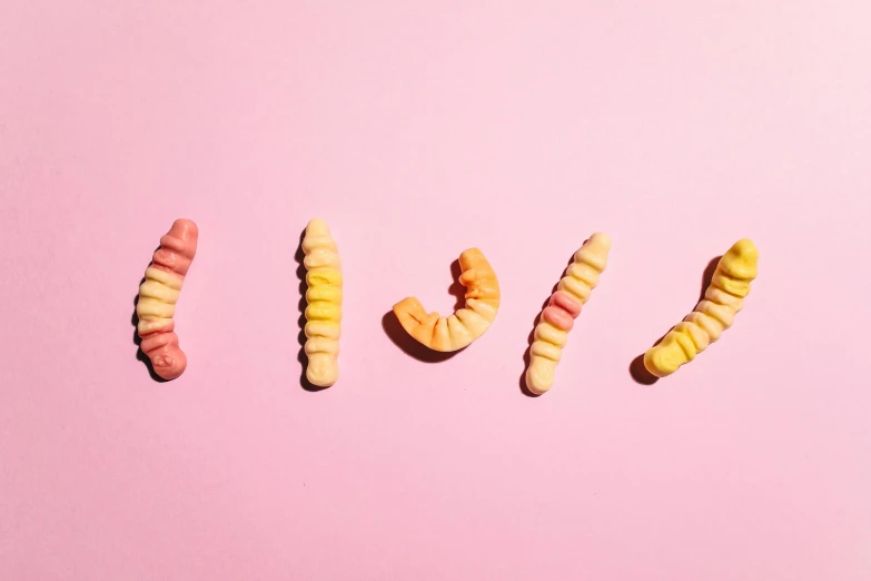 the word i love spelled in candy worms on a pink background, by Rachel Reckitt, trending on pexels, letterism, body made out of macaroni, orange pastel colors, in a row, about to consume you