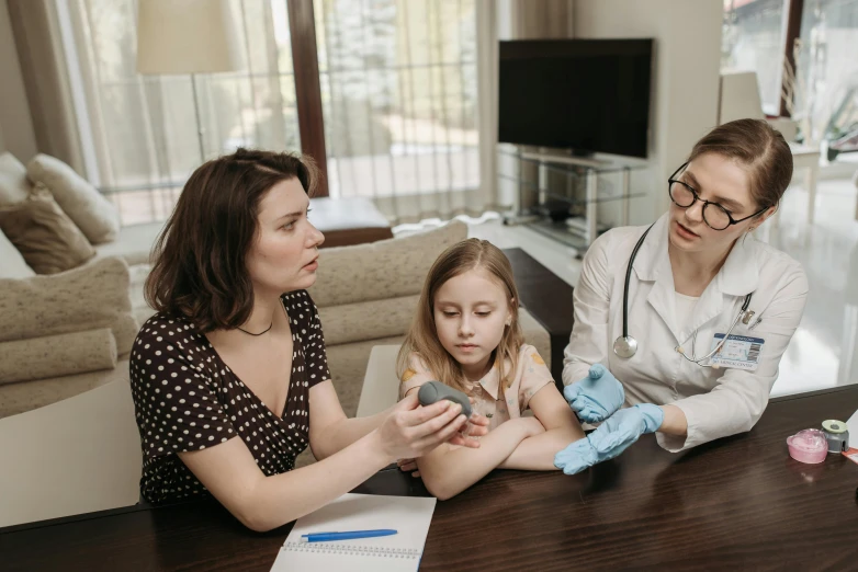 a woman sitting at a table with a little girl, diagnostics, partially cupping her hands, cellular, grey