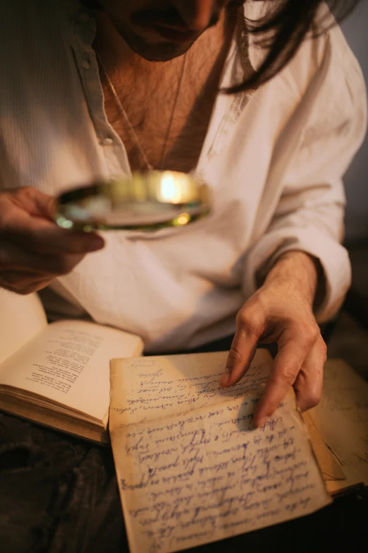 a woman holding a magnifying glass over a book, an album cover, pexels, renaissance, old man, with some hand written letters, focused light, holding a bottle of arak