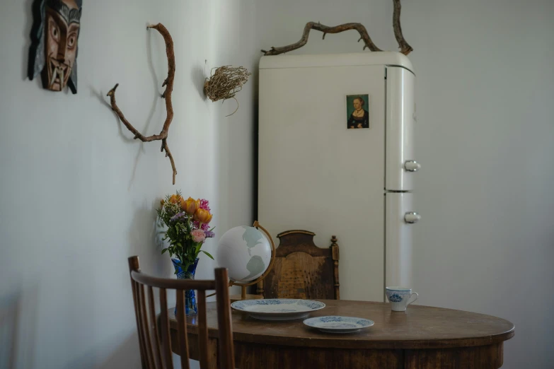 a white refrigerator sitting next to a wooden table, a still life, inspired by Óscar Domínguez, unsplash, overhanging branches, decorated with soviet motifs, portait photo