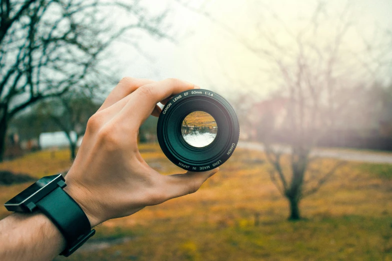 a person taking a picture with a camera, a picture, pexels contest winner, refractions on lens, nature outside, spherical lens, vintage photography