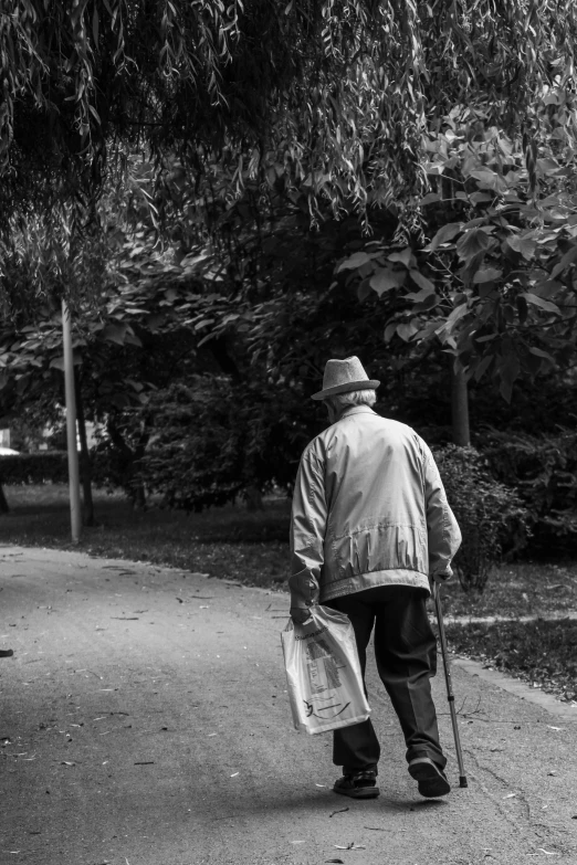 a black and white photo of a man walking down a sidewalk, two frail, in the park, clean streets, walking at the garden