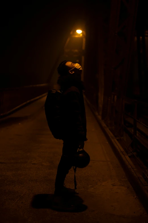 a person standing on a sidewalk at night, inspired by Elsa Bleda, pexels contest winner, graffiti, dark visor covering face, high walled tunnel, with a backpack, hazy