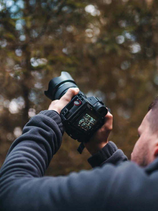 a man taking a picture with a camera, unsplash contest winner, in front of a forest background, home video footage, close up dslr photo, today\'s featured photograph 4k