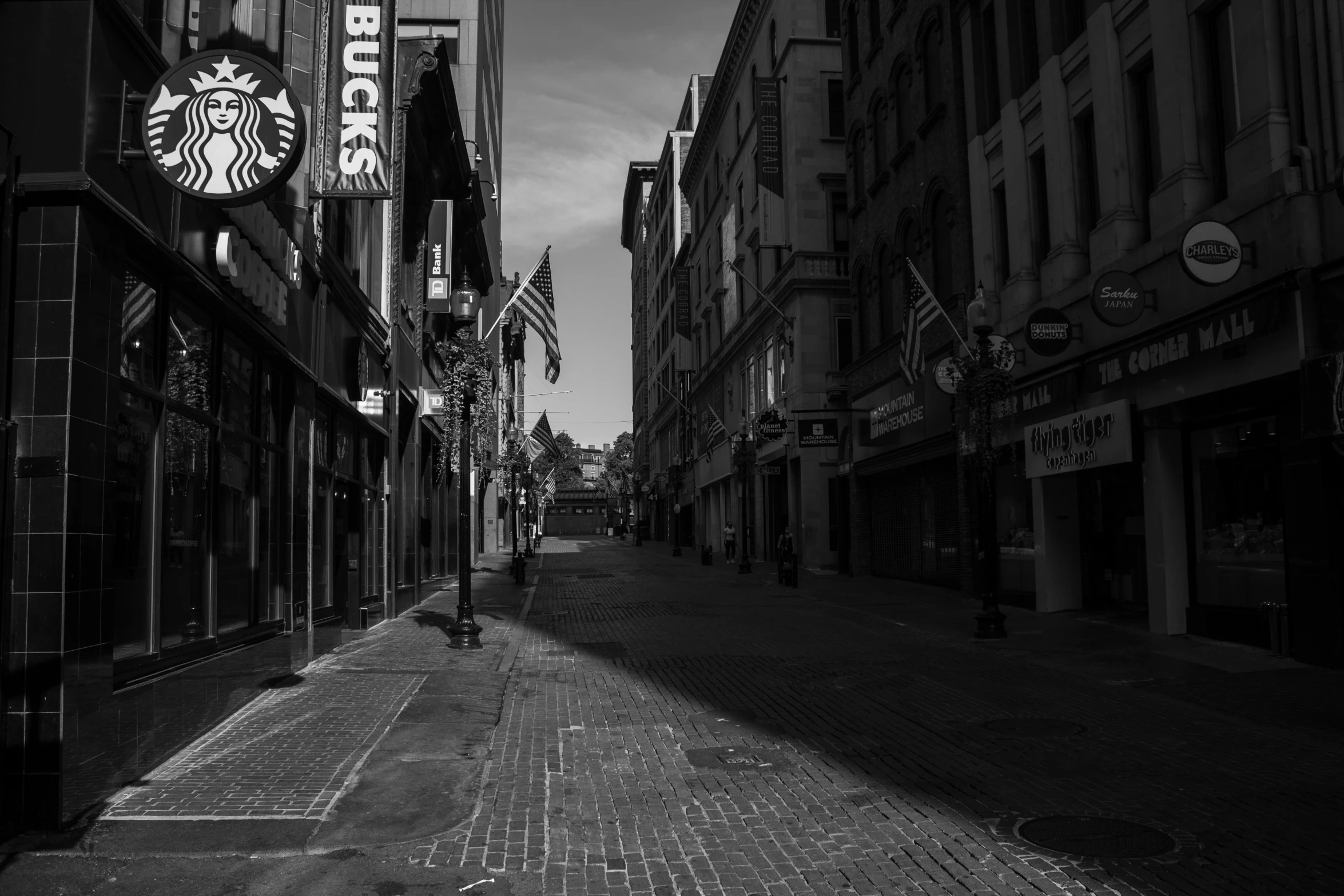 a black and white photo of a starbucks sign, a black and white photo, by Dennis Flanders, pexels, excessivism, empty streets, photograph of the city street, cobblestone street, morning golden hour