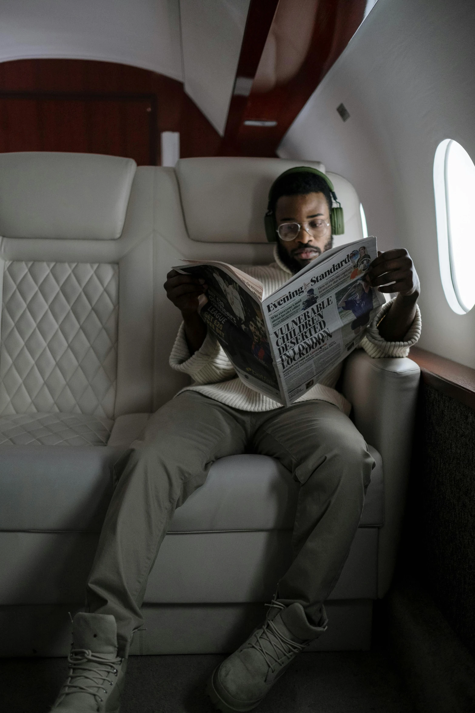 a man sitting in an airplane reading a newspaper, an album cover, pexels contest winner, afrofuturism, donald glover, mo salah, jaylen brown, flaunting his wealth