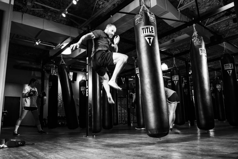 a man standing on a punching bag in a gym, a photo, happening, floating in the air, in fighter poses, bryan sola, detailed and complex