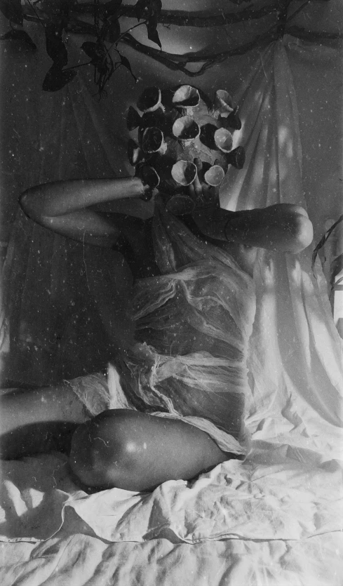 a black and white photo of a woman laying on a bed, inspired by Claude Cahun, gas mask, covered in bandages, light leaks, ffffound