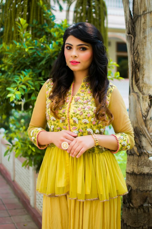 a woman standing next to a tree wearing a yellow dress, inspired by Saurabh Jethani, yellow and olive color scheme, beautiful”