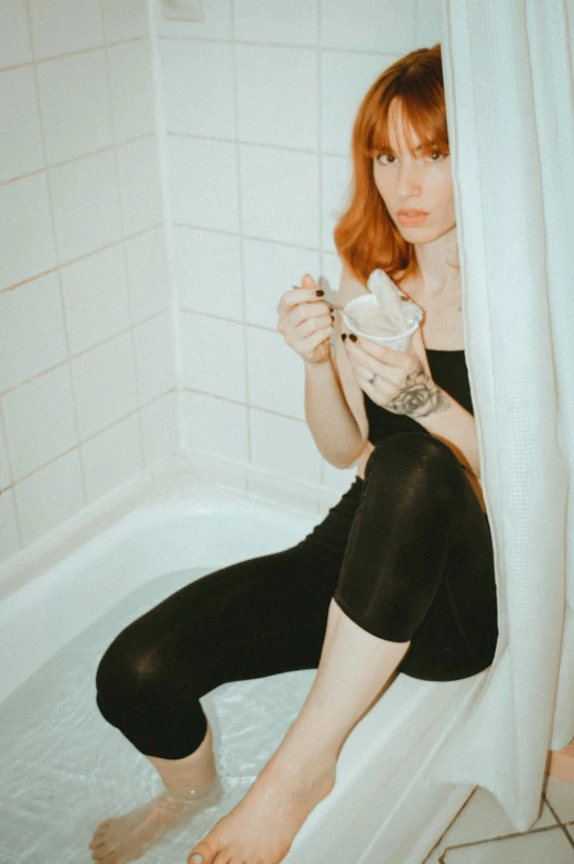 a woman sitting on the edge of a bath tub, an album cover, inspired by Elsa Bleda, trending on pexels, ( redhead, drinking cough syrup, wearing a black bodysuit, (12x) extremely pale white skin