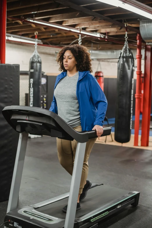 a woman running on a treadmill in a gym, a portrait, featured on reddit, wearing a hoodie and sweatpants, full body within frame, full figured, promo image