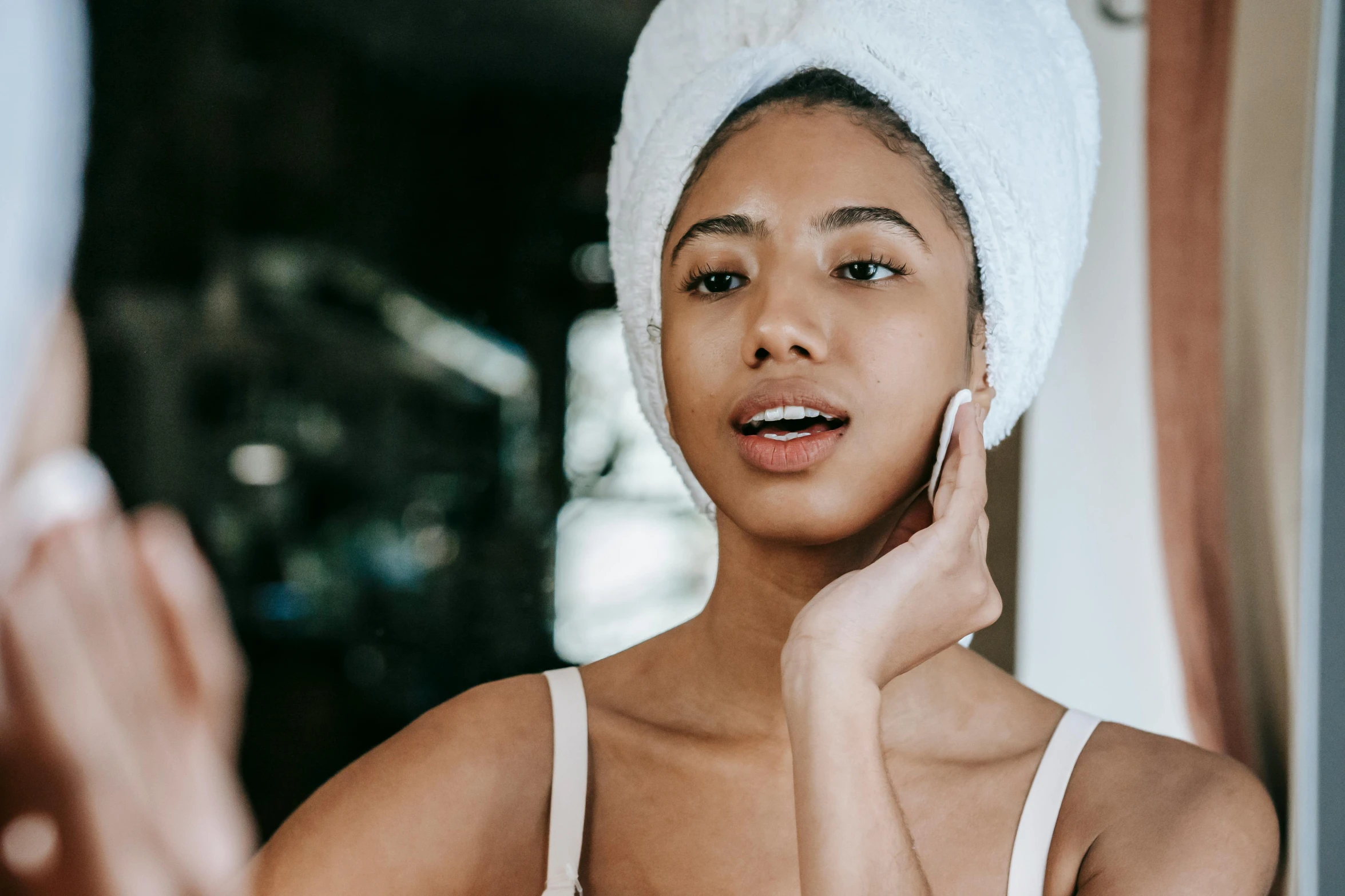 a woman with a towel on her head talking on a cell phone, a portrait, by Julia Pishtar, trending on pexels, happening, square facial structure, mixed-race woman, manuka, skin care