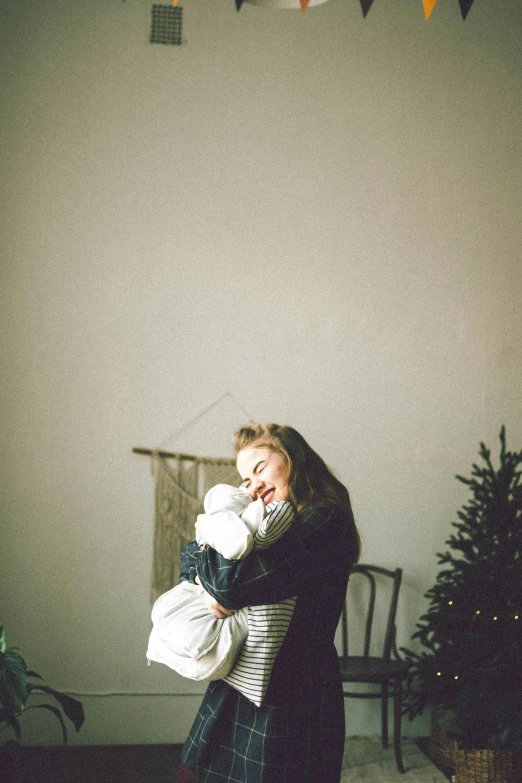 a woman holding a baby in her arms, inspired by Elsa Bleda, unsplash, christmas night, shot on superia 400 filmstock, florence pugh, cozy wallpaper