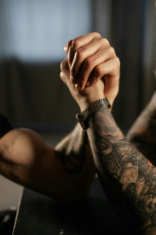 a close up of a person with tattoos on their arms, two muscular men entwined, holding hands, still photograph, medium - shot