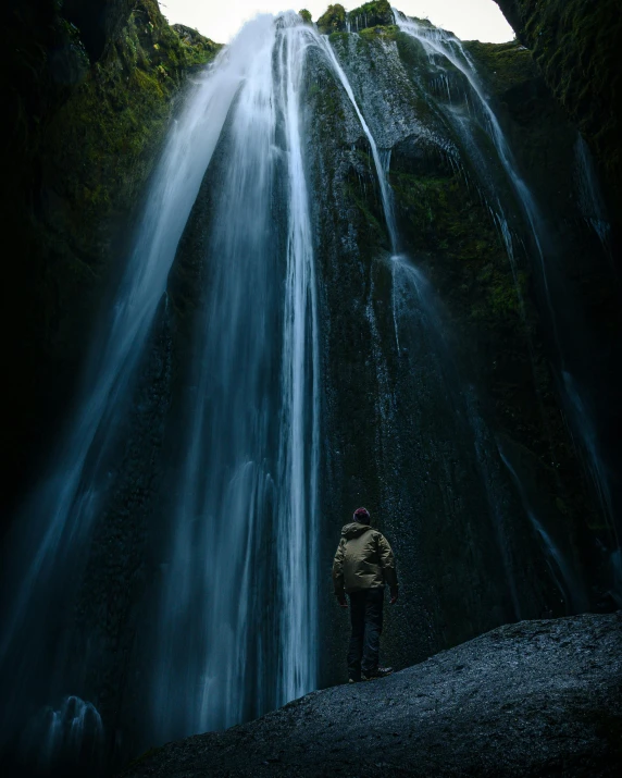 a man standing in front of a waterfall, by Johannes Voss, unsplash contest winner, renaissance, low key light, tourist photo, ilustration, trending photo