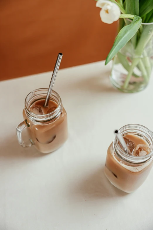 two glasses of iced coffee next to a vase of tulips, trending on pexels, made of brushed steel, with a straw, thumbnail, cafe