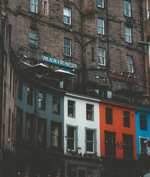 a row of multicolored buildings on a city street, a photo, pexels contest winner, scottish, view from bottom, portrait photo, painted