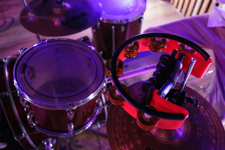 a close up of a drum set on a table, by Joe Bowler, red and purple, the ultimate gigachad, soft rim light, band