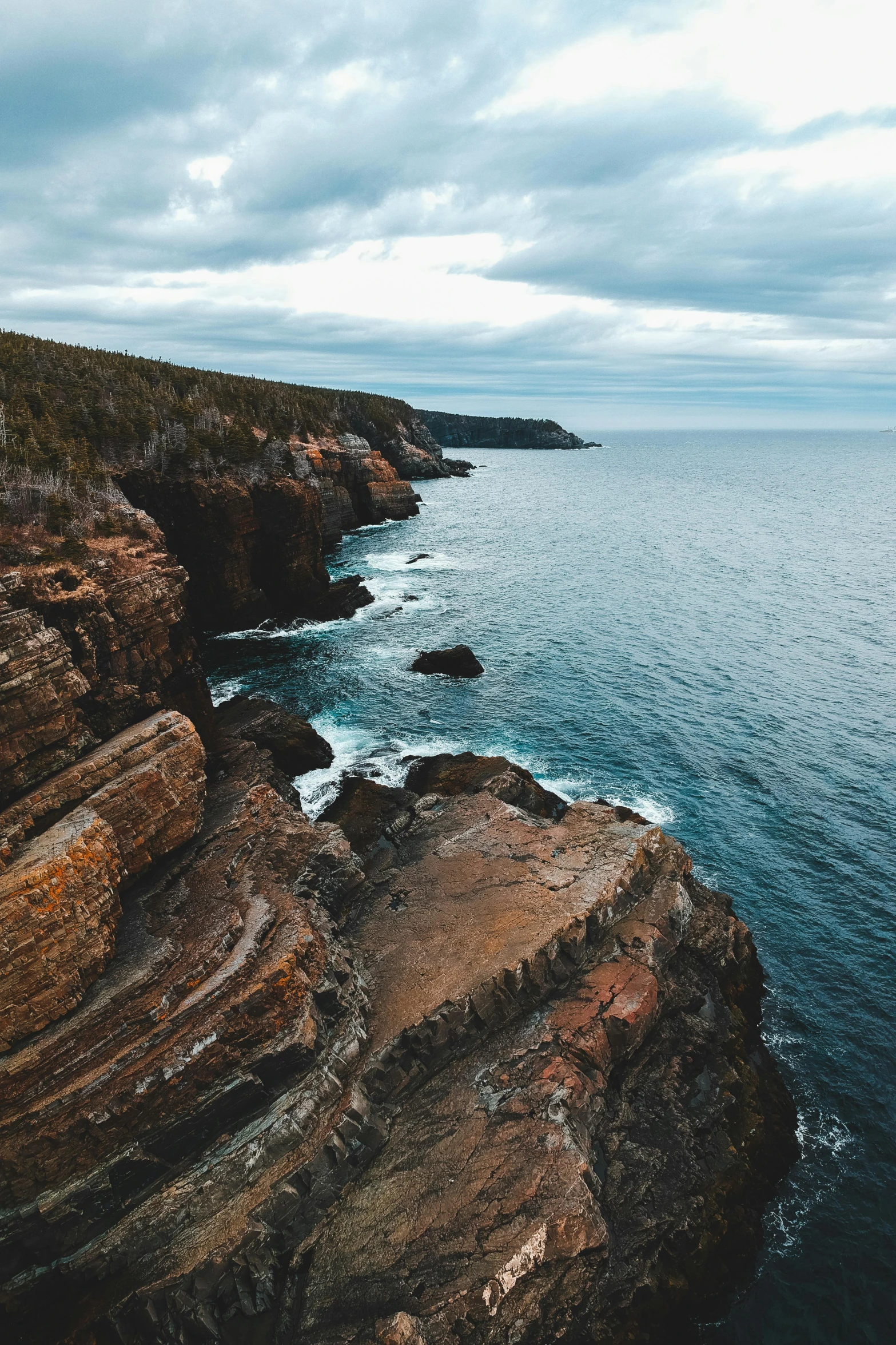 a man standing on top of a cliff next to the ocean, by Kristin Nelson, pexels contest winner, australian tonalism, high view, rocky cliffs, multiple layers, low quality photo