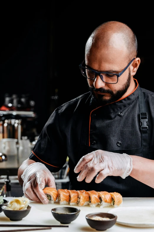 a chef preparing sushi rolls in a restaurant kitchen, a portrait, inspired by Antonio Saura, pexels contest winner, chorizo sausage, on black background, wearing lab coat and glasses, indian master