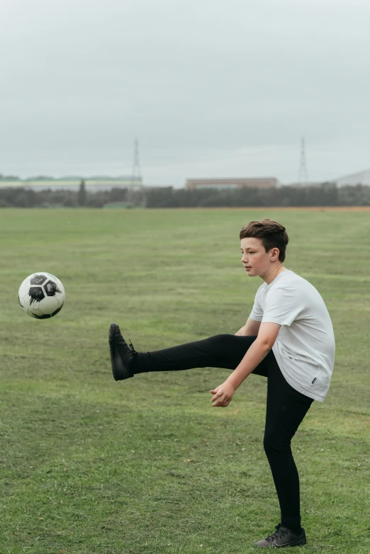 a young man kicking a soccer ball on a field, by James Morris, pexels contest winner, declan mckenna, tom holland, 15081959 21121991 01012000 4k