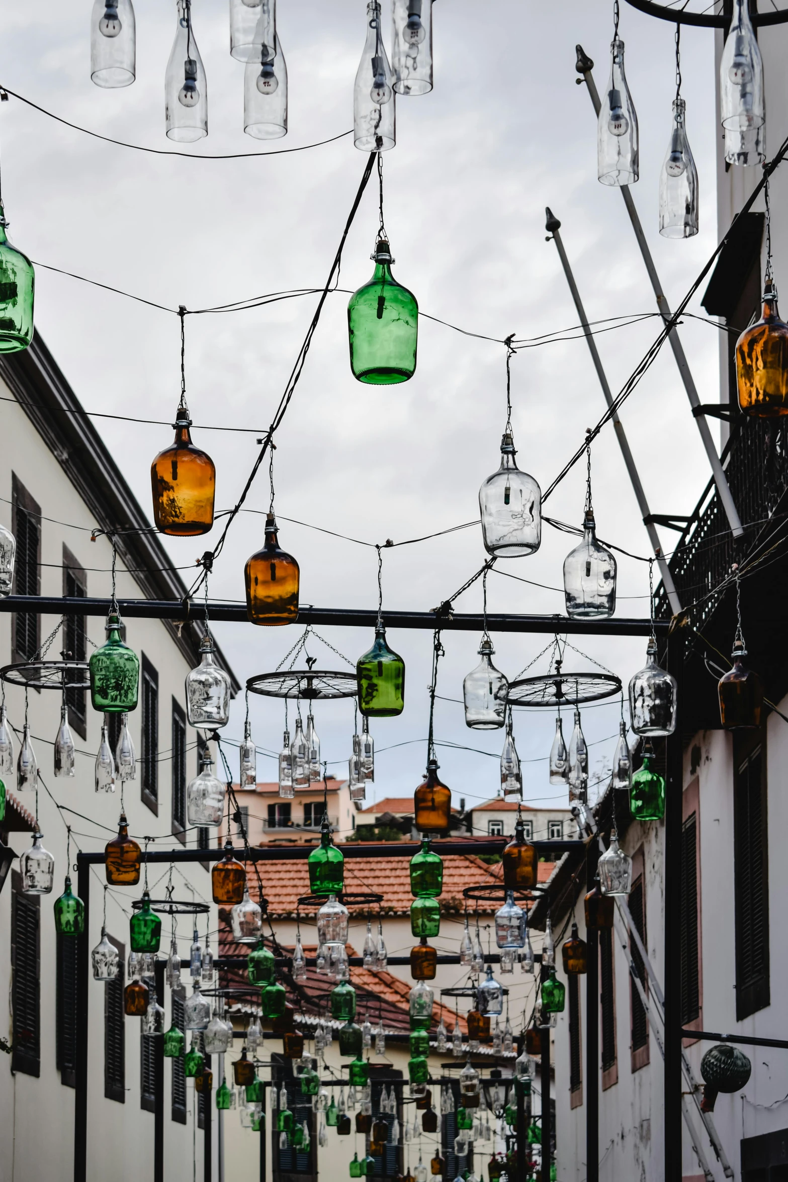 a street filled with lots of green and yellow bottles, kinetic art, farol da barra, gothic lighting, white buildings with red roofs, julia hetta