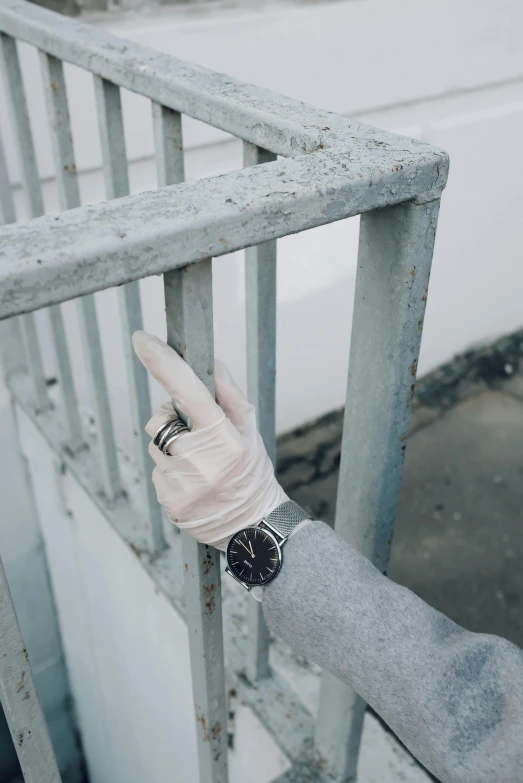 a close up of a person with a glove on, inspired by Elsa Bleda, graffiti, silver sports watch, circular gate in a white wall, vsco, gray concrete