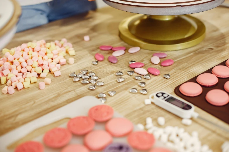 a cake sitting on top of a wooden table, a still life, inspired by Damien Hirst, rose gold heart, pills, medium close up, making of