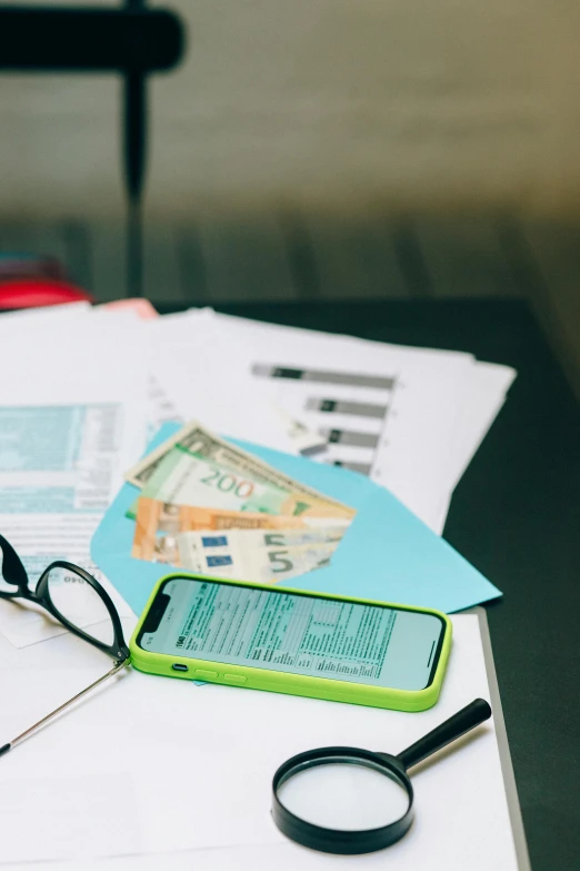 a cell phone sitting on top of a table next to a pile of papers, zoomed view of a banknote, sat at a desk, high-quality photo, illustration »