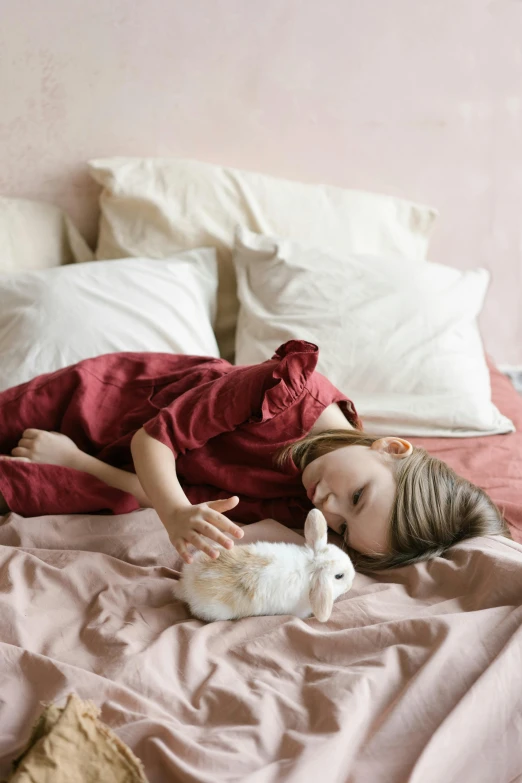 a little girl laying on a bed with a bunny, inspired by Elsa Bleda, pexels contest winner, greta thunberg, woman very tired, linen, pink