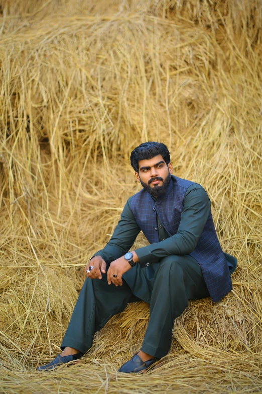 a man sitting on top of a pile of hay, by Riza Abbasi, pexels contest winner, qajar art, handsome man, headshot profile picture, desi, wearing hay coat