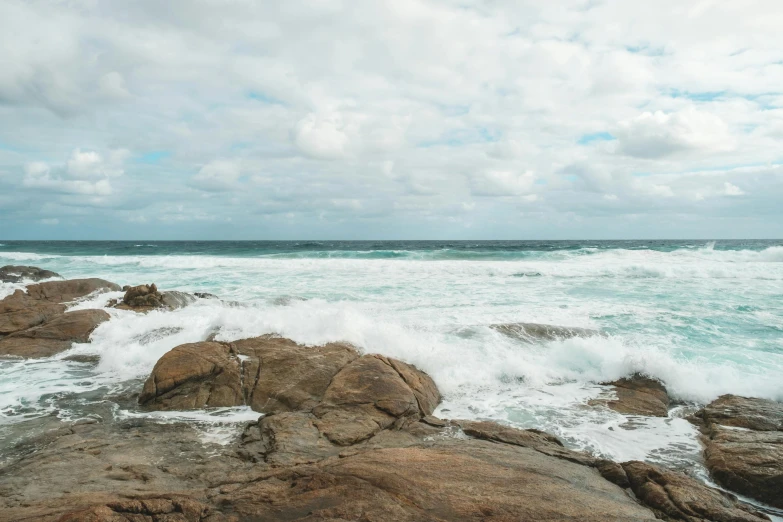 a man standing on top of a rock next to the ocean, pexels contest winner, minimalism, waves crashing at rocks, whealan, low quality photo, panoramic shot