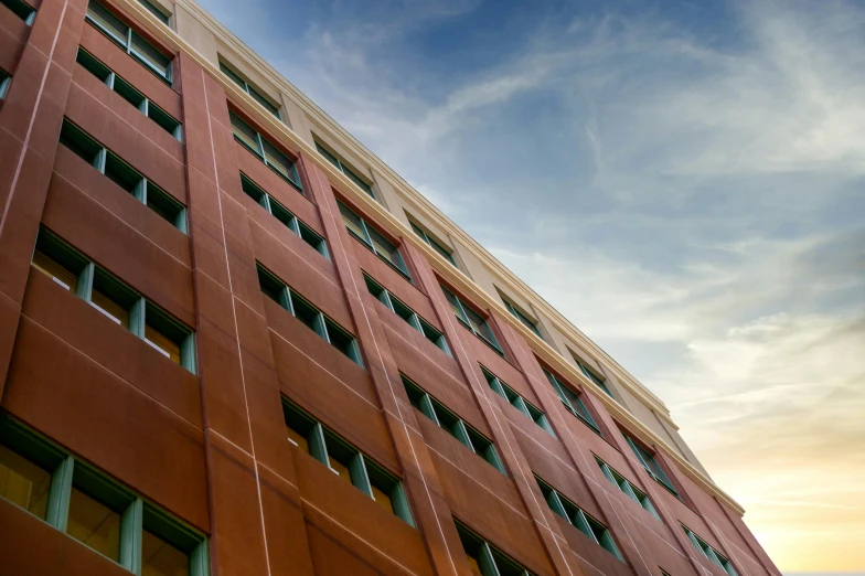 a tall red building with lots of windows, a photo, by Washington Allston, unsplash, fan favorite, global illumination hdri, bottom angle, late afternoon