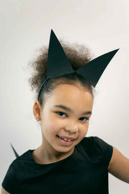 a little girl with a pair of scissors in her hair, inspired by Tex Avery, doja cat as cat woman, wearing a paper crown, matte black paper, product introduction photo