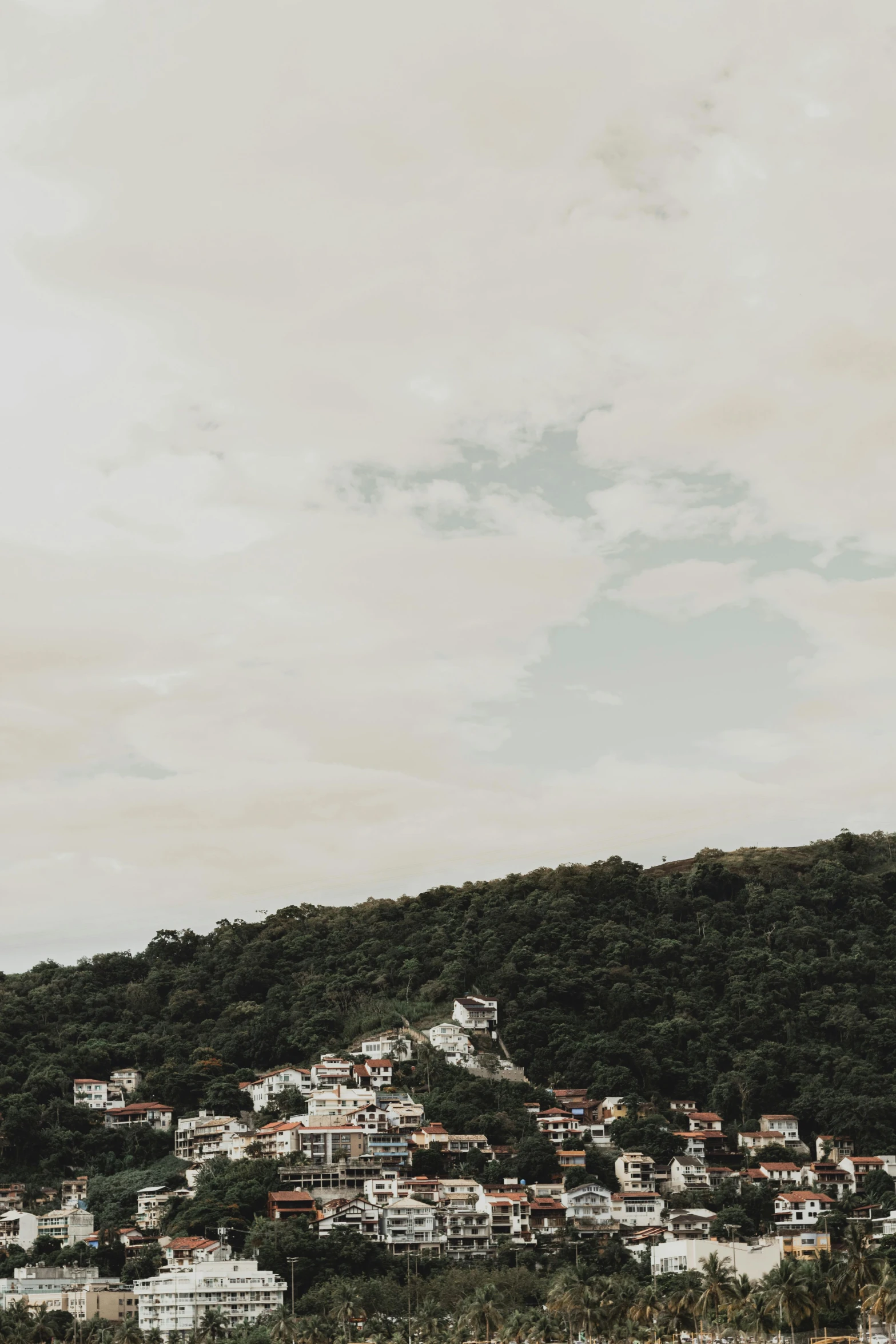 a large body of water next to a lush green hillside, by Tobias Stimmer, pexels contest winner, white buildings, gloomy earthy colors, trending on vsco, guanajuato