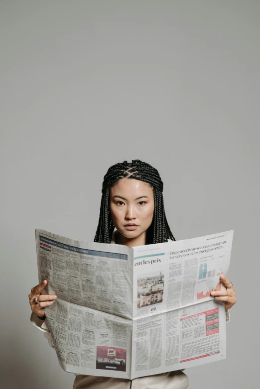 a woman holding a newspaper in front of her face, by Fei Danxu, trending on pexels, girl with plaits, studio shoot, ethnicity : japanese, looking distracted