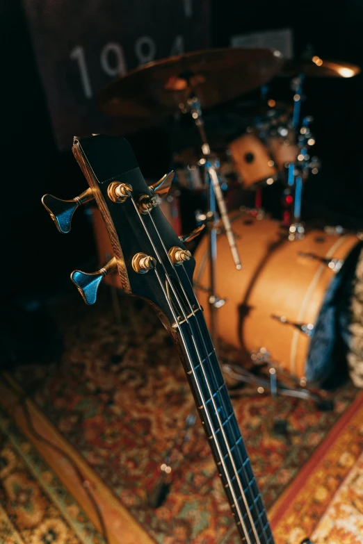 a guitar sitting on top of a carpet next to a drum, up-close, double bass, studio recording, zoomed in