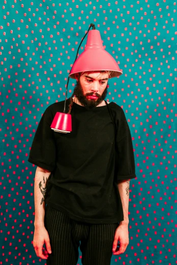 a man with a pink hat on his head, an album cover, inspired by Juan de Valdés Leal, neo-dada, with a beard and a black shirt, lights off, photo from a promo shoot, wearing a baggy