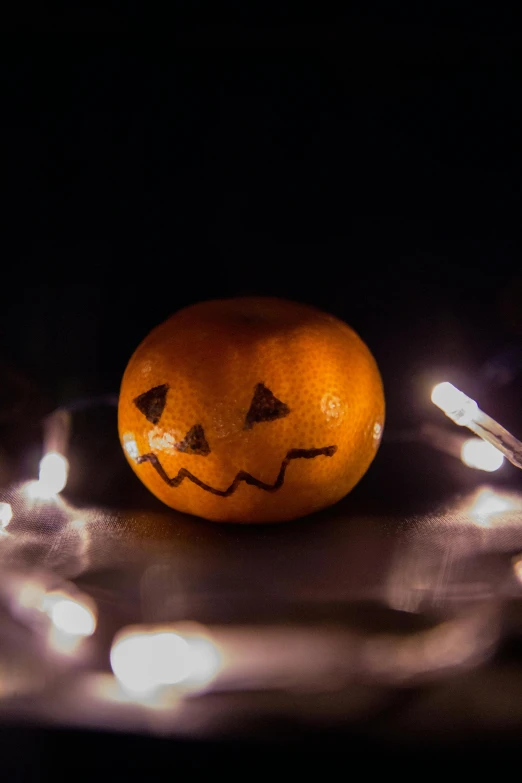 an orange sitting on top of a table covered in lights, spooky lighting, snacks, light stubble, dark. no text