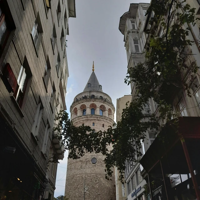 a tall clock tower towering over a city street, by Tom Wänerstrand, pexels contest winner, art nouveau, ottoman sultan, view from ground level, gif, shot on canon eos r5