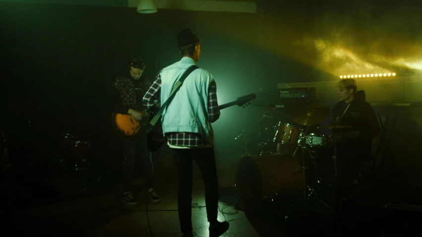 a group of men standing next to each other on a stage, an album cover, inspired by Elsa Bleda, pexels contest winner, band playing, dark hazy room, performing a music video, indoor scene