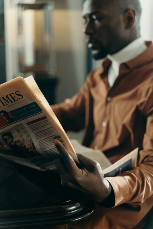 a man sitting in a chair reading a newspaper, pexels contest winner, dark skinned, brown clothes, ad image, thumbnail