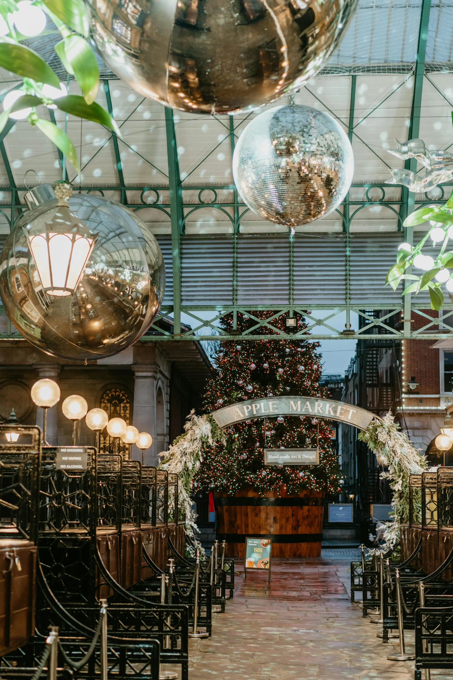 a room filled with lots of tables and chairs, inspired by Ernest William Christmas, steel archways, festive, lush plants and lanterns, cyber copper spiral decorations