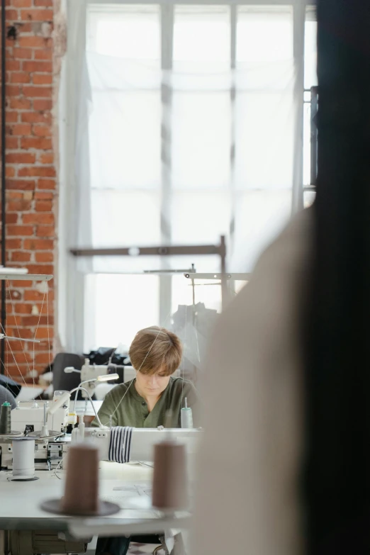 a woman working at a sewing machine in a factory, by Winona Nelson, trending on unsplash, renaissance, big windows, designer clothes, low quality photo, profile picture