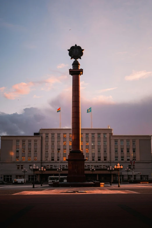 a large building with a clock tower in front of it, a statue, by Sven Erixson, unsplash, berlin secession, norilsk, sundown, colonnade, presidential cross