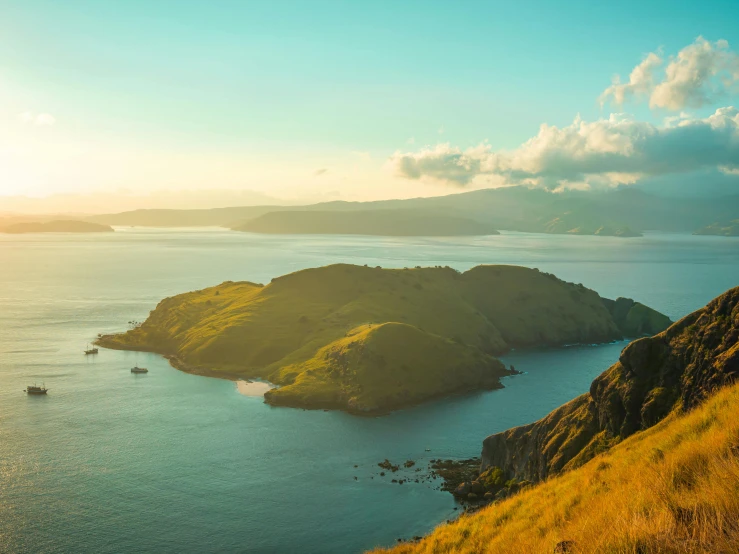 a large body of water next to a lush green hillside, pexels contest winner, sumatraism, golden hour sun, islands, maori, conde nast traveler photo