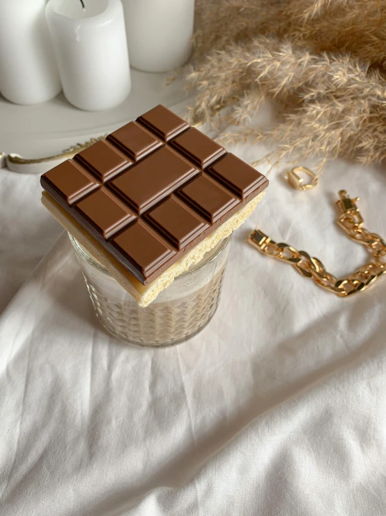 a piece of chocolate sitting on top of a table, wearing gold detailed choker, soey milk, squares, thumbnail