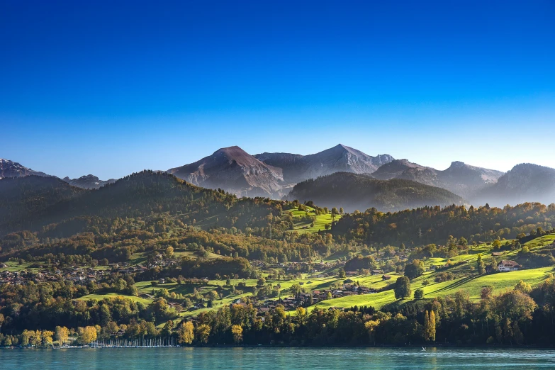 a large body of water with mountains in the background, by Karl Stauffer-Bern, pexels contest winner, renaissance, hillside, sunny morning light, conde nast traveler photo, screensaver